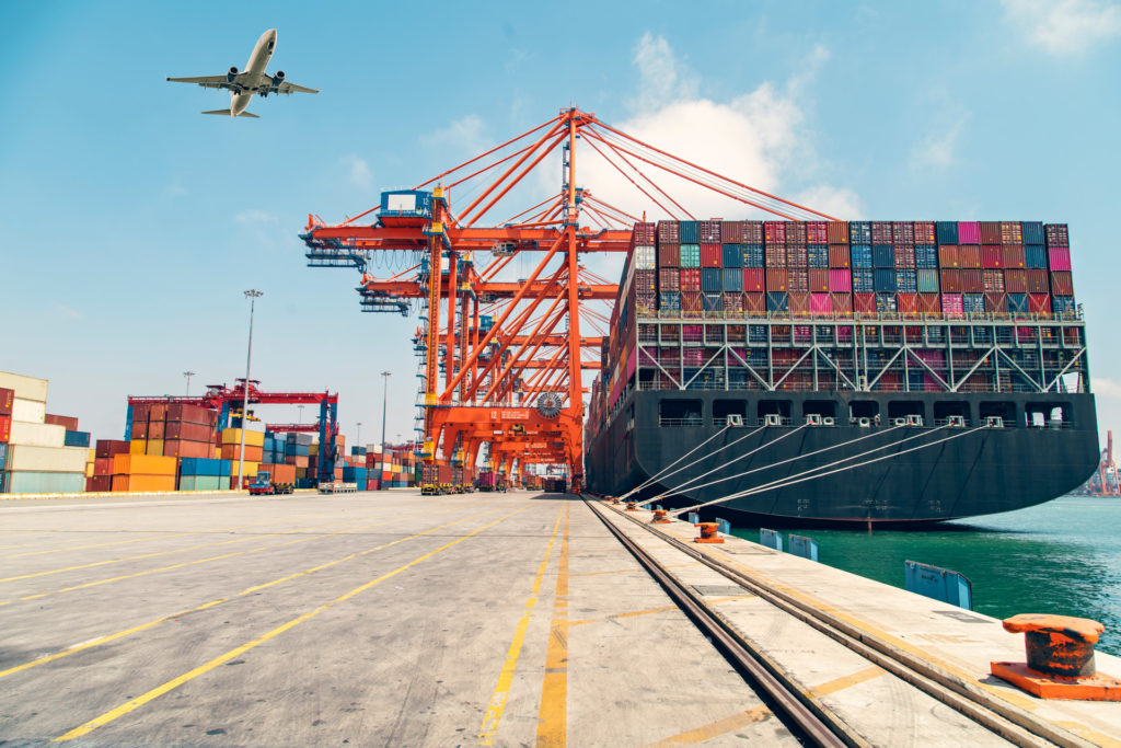 Airplane flying above container port